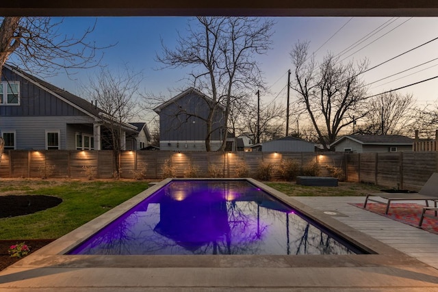 pool at dusk with a fenced in pool and a fenced backyard