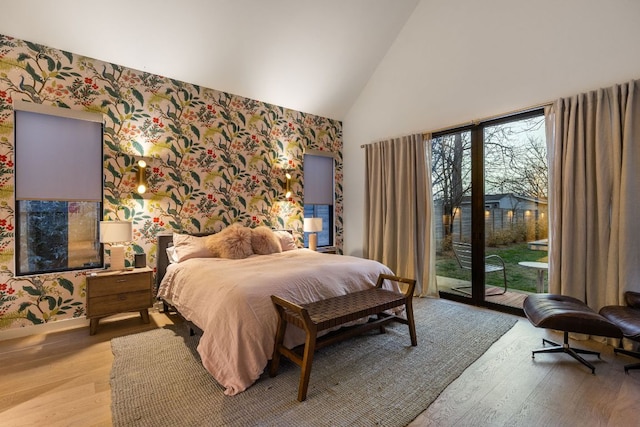 bedroom featuring baseboards, high vaulted ceiling, wallpapered walls, light wood-style flooring, and access to outside