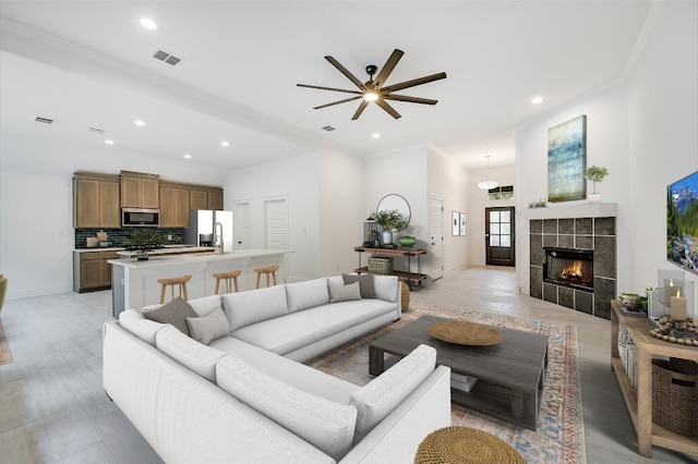 living room featuring crown molding, recessed lighting, visible vents, and a tile fireplace