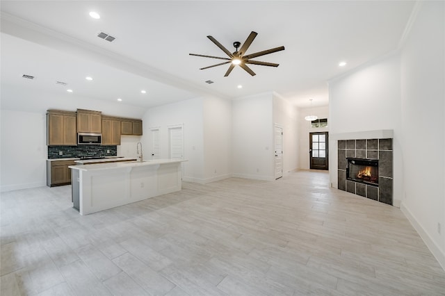 kitchen featuring stainless steel microwave, visible vents, open floor plan, a fireplace, and a sink