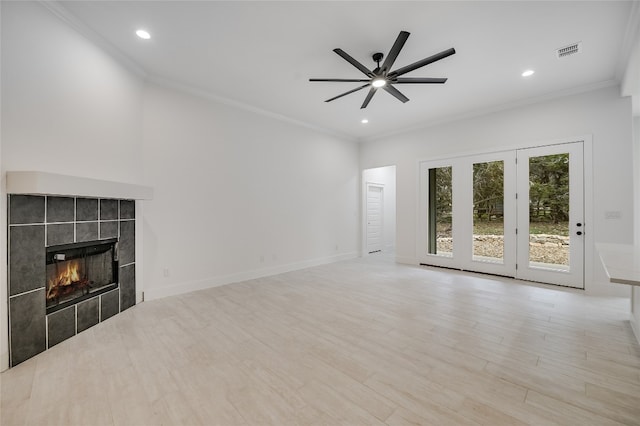 unfurnished living room featuring visible vents, baseboards, ornamental molding, a tile fireplace, and wood finished floors