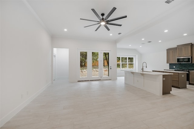 kitchen featuring a kitchen island with sink, a sink, decorative backsplash, stainless steel appliances, and open floor plan