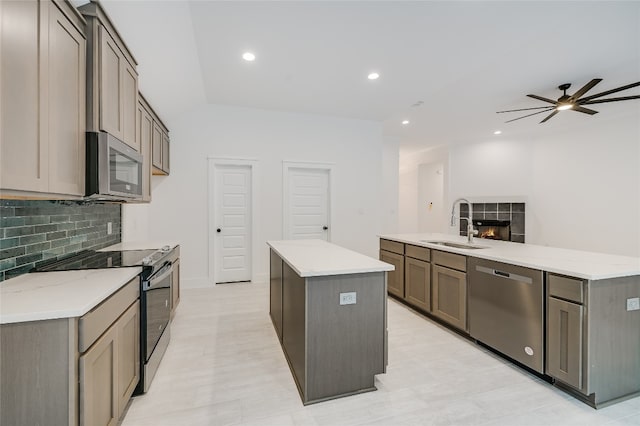 kitchen with backsplash, a center island, appliances with stainless steel finishes, a fireplace, and a sink