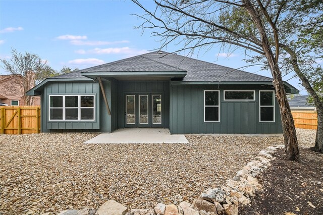 rear view of house with a patio, fence, and board and batten siding