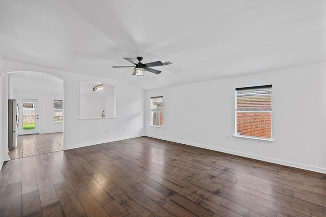 unfurnished room featuring baseboards, arched walkways, a ceiling fan, and dark wood-style flooring