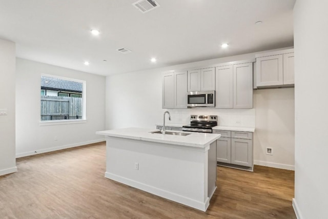 kitchen featuring visible vents, appliances with stainless steel finishes, wood finished floors, and a sink