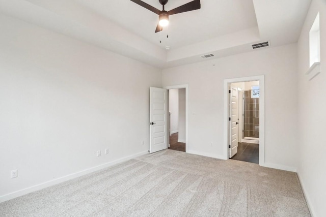 unfurnished bedroom featuring visible vents, a raised ceiling, baseboards, and carpet floors