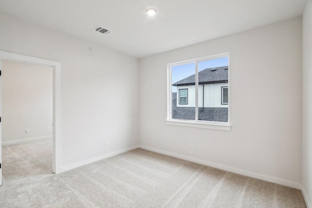 empty room featuring light carpet, visible vents, and baseboards