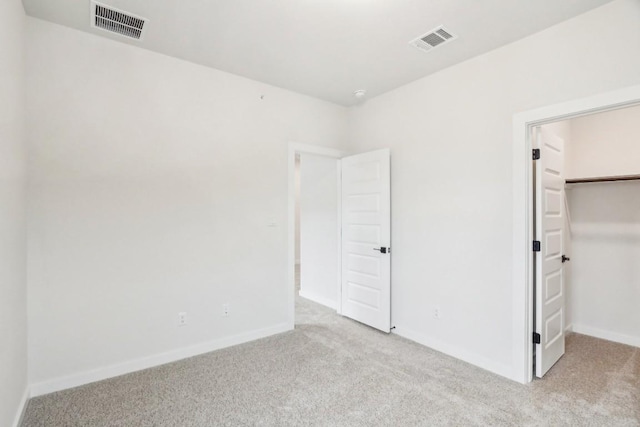 unfurnished bedroom with visible vents, a walk in closet, and carpet floors