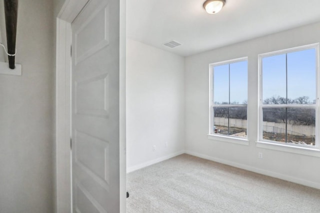 carpeted spare room featuring visible vents and baseboards