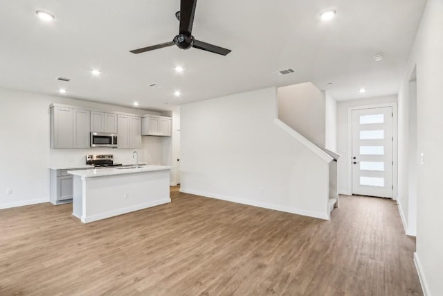 kitchen with light wood-type flooring, visible vents, a sink, open floor plan, and stainless steel appliances