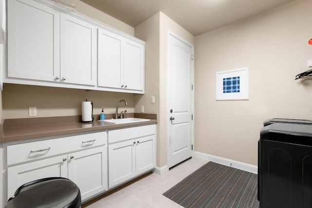 laundry area with a sink, baseboards, cabinet space, and washer / clothes dryer