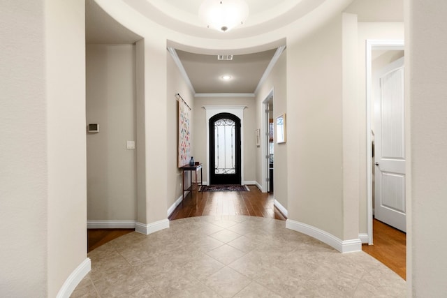 foyer entrance featuring tile patterned flooring, visible vents, baseboards, and ornamental molding