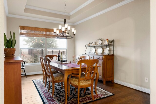 dining room featuring baseboards, a raised ceiling, ornamental molding, and hardwood / wood-style flooring