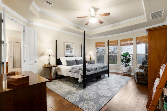 bedroom with a raised ceiling, hardwood / wood-style flooring, and visible vents