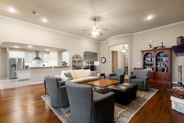 living area featuring hardwood / wood-style flooring, baseboards, arched walkways, and ceiling fan