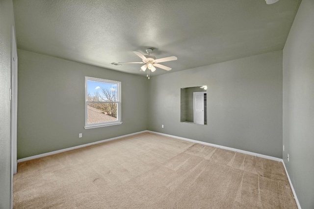 carpeted spare room with visible vents, ceiling fan, a textured ceiling, and baseboards