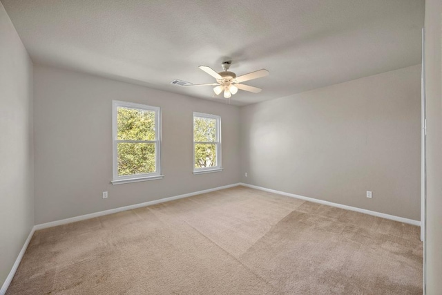 empty room with ceiling fan, baseboards, visible vents, and light carpet