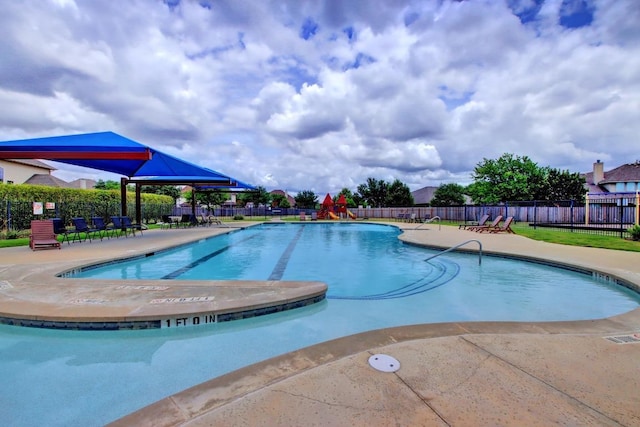 community pool with a patio area and fence