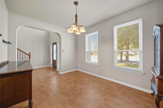 foyer featuring arched walkways, stairway, a chandelier, and baseboards