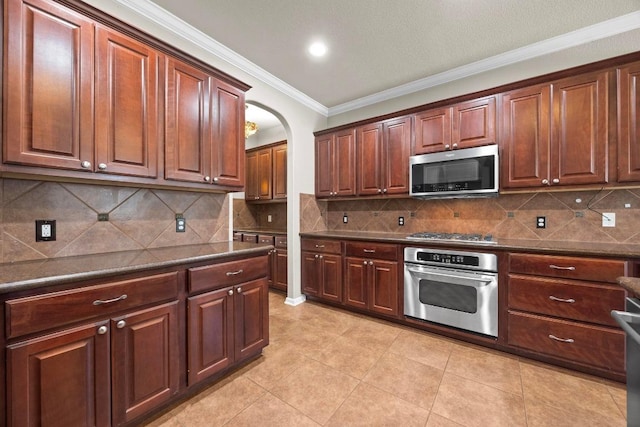 kitchen with stainless steel appliances, tasteful backsplash, dark countertops, and crown molding