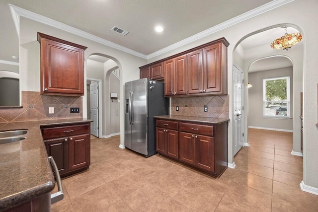 kitchen with visible vents, stainless steel fridge, arched walkways, crown molding, and baseboards