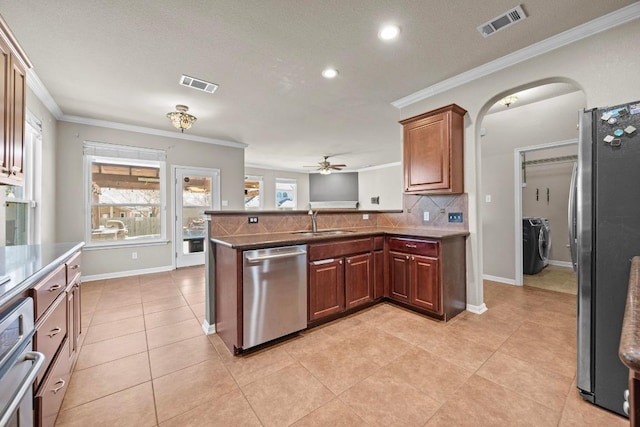 kitchen with visible vents, arched walkways, a sink, appliances with stainless steel finishes, and washing machine and dryer