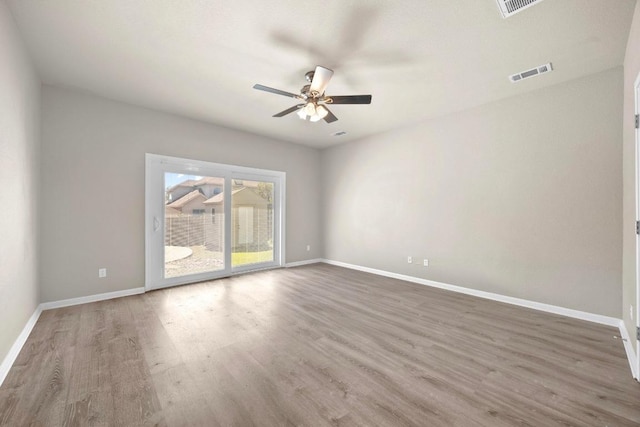 empty room featuring visible vents, baseboards, and wood finished floors