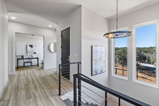 hallway with baseboards, an upstairs landing, recessed lighting, an inviting chandelier, and wood finished floors