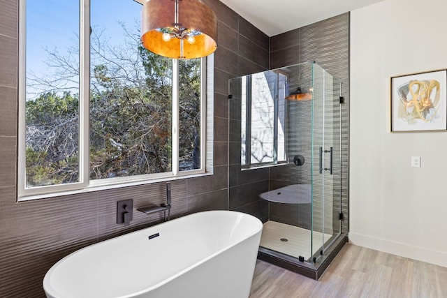 bathroom featuring a shower stall, a soaking tub, wood finished floors, and baseboards