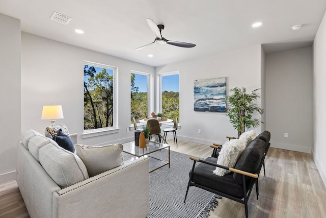 living room with a ceiling fan, visible vents, baseboards, recessed lighting, and light wood-type flooring