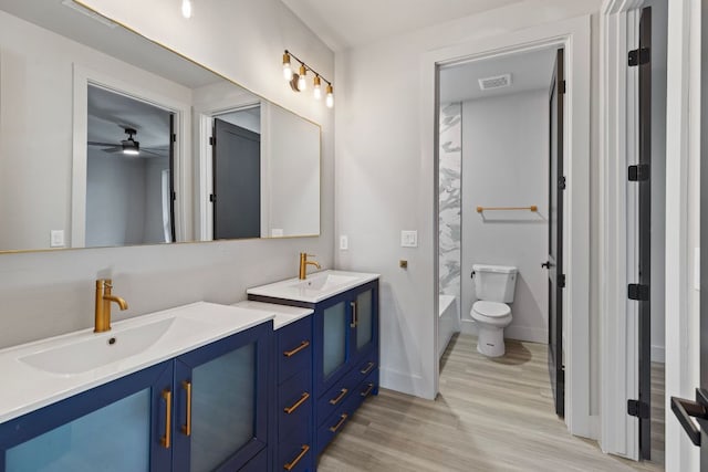 full bath with wood finished floors, visible vents, double vanity, a sink, and toilet