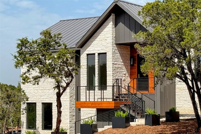 view of side of property with stone siding, board and batten siding, and a standing seam roof