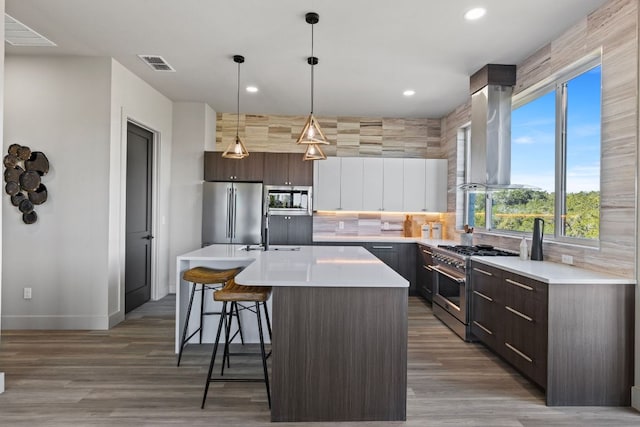 kitchen with visible vents, a kitchen bar, decorative backsplash, island exhaust hood, and high end appliances