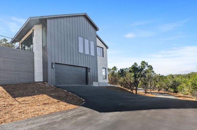 view of side of home with an attached garage, board and batten siding, and driveway