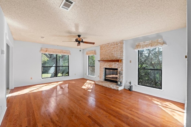 unfurnished living room featuring visible vents, baseboards, a fireplace, a ceiling fan, and wood-type flooring