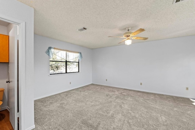 empty room featuring carpet flooring, a ceiling fan, visible vents, and a textured ceiling