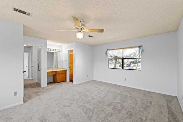 unfurnished bedroom featuring a textured ceiling, baseboards, visible vents, and light carpet