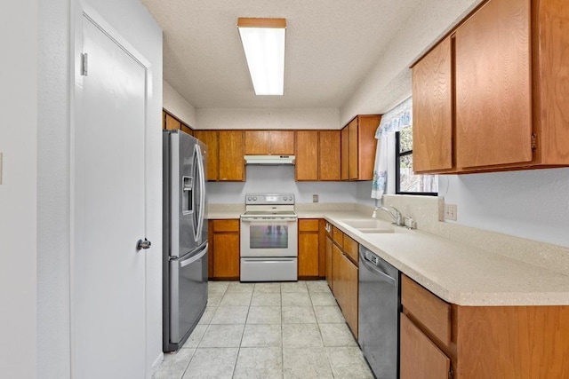 kitchen featuring brown cabinets, appliances with stainless steel finishes, light countertops, and a sink