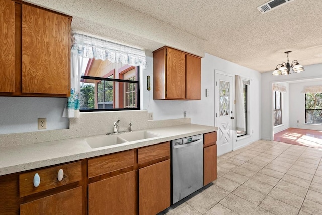 kitchen with visible vents, light countertops, stainless steel dishwasher, brown cabinetry, and a sink