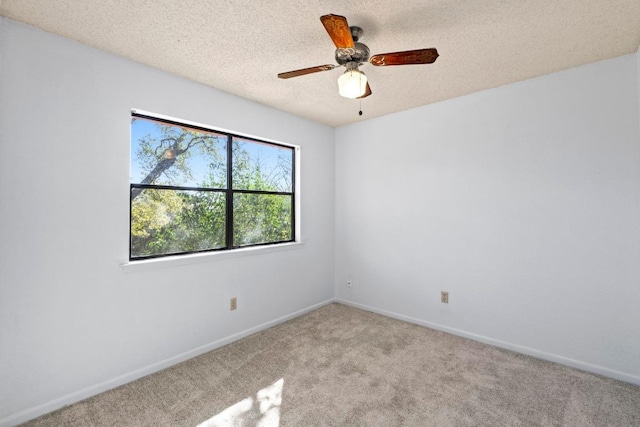 carpeted spare room featuring a ceiling fan, baseboards, and a textured ceiling