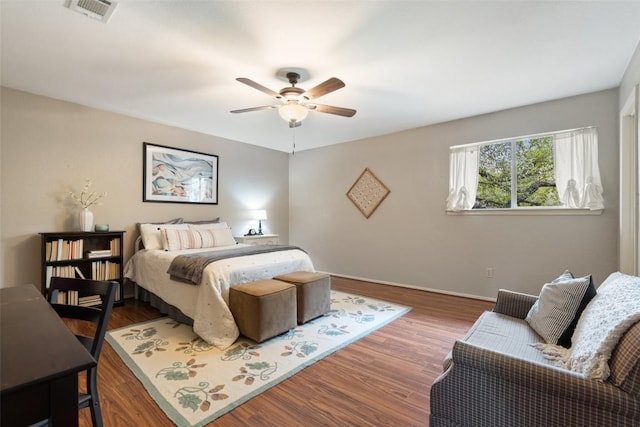 bedroom featuring baseboards, wood finished floors, visible vents, and ceiling fan