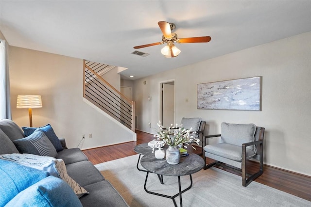 living area featuring visible vents, a ceiling fan, wood finished floors, stairway, and baseboards