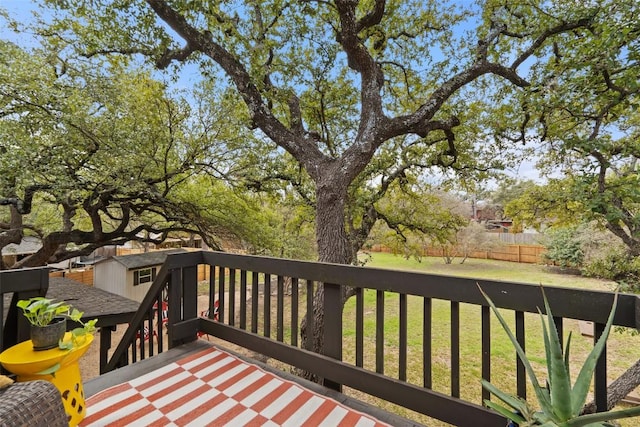 wooden terrace with an outdoor structure, a yard, fence, and a storage unit