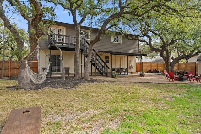 back of property with a patio area, a yard, stairs, and a fenced backyard