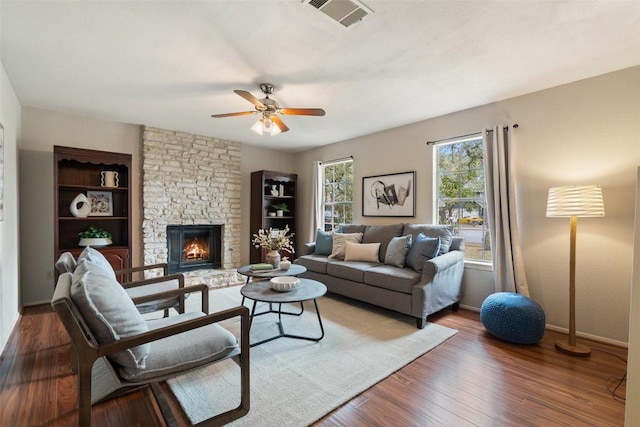 living area featuring visible vents, wood finished floors, a fireplace, baseboards, and ceiling fan