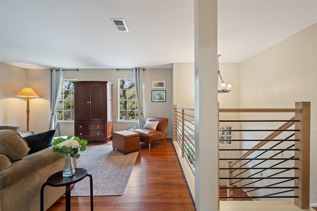 living room featuring a notable chandelier, visible vents, and dark wood-style flooring