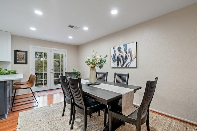 dining room featuring visible vents, light wood-type flooring, recessed lighting, french doors, and a textured wall