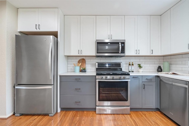 kitchen featuring light countertops, light wood-style floors, appliances with stainless steel finishes, and gray cabinetry