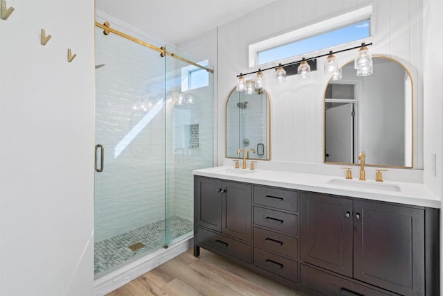 bathroom with a shower stall, wood finished floors, double vanity, and a sink